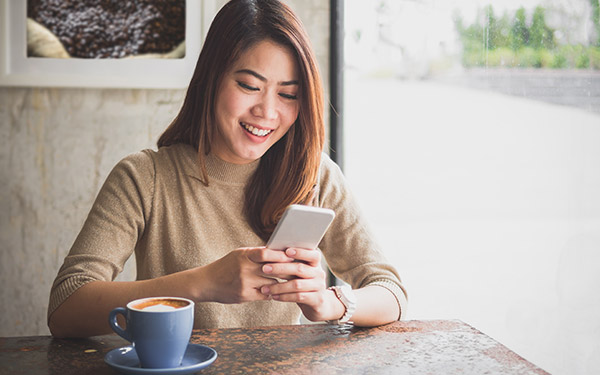 Woman with a cellphone and a cup of coffee